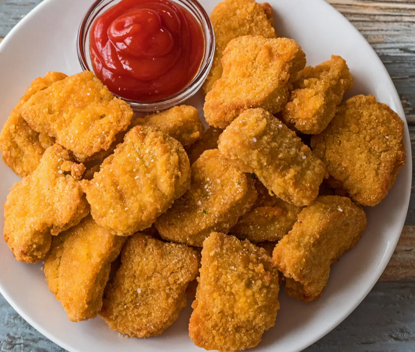 a plate of chicken nuggets with ketchup on the side